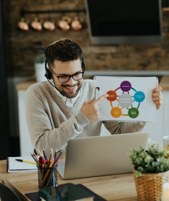 Young happy businessman examining diagram while having virtual meeting over laptop at home.
